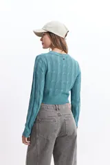 Sweater de punto color mostaza, con diseño de ochos y textura calada. Tiene cuello redondo, mangas largas y terminaciones acanaladas en puños y cintura.