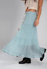 Pollera larga de color rosa pálido, con corte en capas y cintura elastizada. Incluye lazo fino del mismo material.