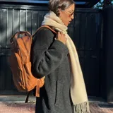 Mochila de eco-cuero color marrón, con múltiples bolsillos frontales y laterales, y asa superior.