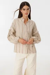 Camisa beige con rayas bordeaux, de corte suelto y mangas abullonadas.