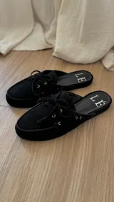 Mules de cuero gamuzado color negro, con detalle de cordones y ojales metálicos.