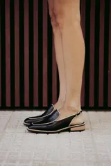 Mocasines slingback negros de cuero con punta cuadrada, ribete en color crudo y hebilla dorada ajustable.