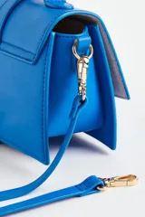 Cartera bandolera azul eléctrico de cuero sintético, con asa corta superior y correa larga extraíble. Tiene solapa con cierre magnético y detalle de hebilla metálica dorada.