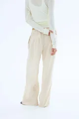 Pantalón de lino color crema, de corte holgado, con cintura elastizada y cordón de ajuste.