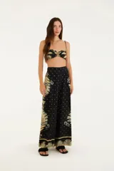 Pantalón recto de viscosa con estampado floral en tonos beige y celeste sobre fondo negro. Tiene cintura alta y corte clásico.