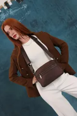 Bandolera color rosa viejo con detalles en cuero marrón claro, múltiples cremalleras metálicas y herrajes plateados. Incluye correa ancha ajustable con el logo de la marca.