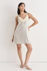 Vestido corto de fiesta, cubierto de lentejuelas plateadas, con escote en V y flecos de tul color crema.