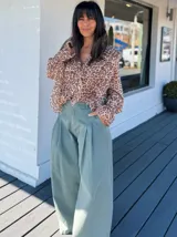Pantalón de jean celeste de corte ancho con pinzas en la cintura y cinturón plateado con apliques florales.