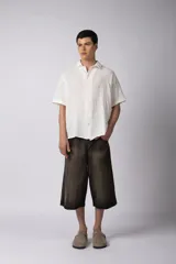 Camisa de manga corta confeccionada en una mezcla liviana de rayón y lino color blanco. Presenta un diseño de calce regular con cuello plano, botones frontales y un estampado artístico en la espalda inspirado en el sol.