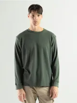 Remera de manga larga verde militar, confeccionada en tela mini piqué de algodón, con cuello redondo y puños en las mangas.