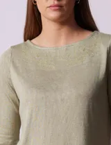 Remera verde con escote redondo y mangas tres cuartos. Presenta bordados en el escote.