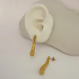 Par de aros colgantes dorados con forma irregular y diseño moderno.