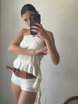 Short blanco de tiro alto con lentejuelas y cinturón marrón con tachas.