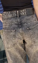 Pantalón jean azul oscuro, de corte wide leg y tiro medio. Presenta detalles de costuras diagonales en la parte superior.