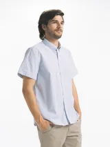 Camisa celeste con estampado de microcuadros blancos, de corte clásico, manga corta y cuello abotonado.