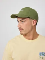 Gorra de lona color salmón con logo de la marca bordado en blanco.