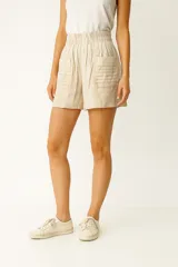 Short de lino y viscosa color beige, con cintura elástica de tiro alto, bolsillos laterales con detalle de costuras horizontales y corte holgado.