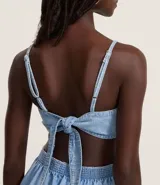 Mono largo de jean celeste con breteles finos ajustables, escote cuadrado, recortes delanteros y laterales abiertos, lazo en la espalda y elástico en la cintura.