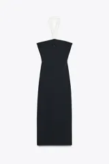 Vestido midi negro de tejido elástico, con escote recto y cuello halter. Presenta un lazo blanco a contraste en el delantero con aplicación de perlas y espalda descubierta.