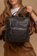 Mochila mediana negra de símil cuero con asa superior, dos compartimentos con cierre y bolsillos frontales.