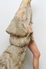 Vestido largo de viscosa con estampado floral, escote en pico, manga tipo capa con aberturas y bajo asimétrico.