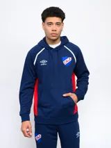 Canguro azul marino de felpa con capucha, cortes laterales rojos, piping blanco en los hombros y logo del Club Nacional de Football bordado en el pecho. Incluye logo de Umbro bordado en blanco.