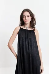 Vestido largo negro con estampado abstracto, de silueta amplia, con breteles finos y escote redondeado. Tiene un frunce sutil en el escote delantero y trasero que genera una caída fluida y relajada.