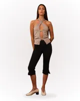 Top color beige con escote halter cruzado y abertura en el centro, con hebillas metálicas.