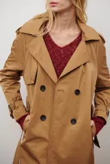 Trench coat largo color beige con doble botonadura, cuello solapa, charreteras en los hombros y puños ajustables con hebillas. Incluye un cinturón a tono.