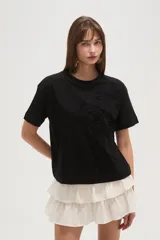 Remera negra de algodón con apliques de moños bordados en el frente, corte ancho y cuello redondo.