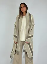 Ruana tipo pashmina color tostado con diseño a cuadros y rayas en tonos beige y marrón. Presenta flecos en los bordes.