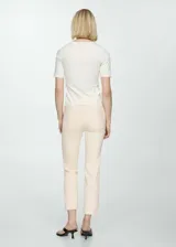 Pantalón de jean color crema, de corte flare y tiro alto, con cinco bolsillos y ruedo desflecado.