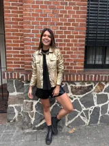 Chaqueta plateada metalizada con cuello camisero, cierre frontal con botones, bolsillos de parche en el pecho y corte recto.