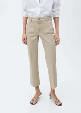 Pantalón de jean color beige, tiro medio, corte flare, con bolsillos de parche delanteros y ruedo desflecado.
