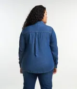 Camisa de jean azul oscuro, de corte clásico, con cuello tradicional, mangas largas con puños abotonados, bolsillo en el pecho y cierre frontal abotonado.