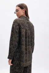 Camisa de manga larga, corte oversize, con cuello camisero y botones frontales. Estampado de patrón orgánico en color dorado sobre fondo negro.