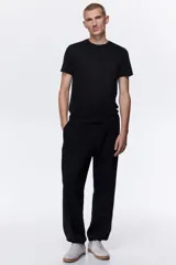 Remera negra de corte ajustado, confeccionada en punto de algodón liviano, con cuello redondo ribeteado y bajo recto.