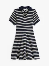 Vestido corto de corte evasé a rayas horizontales azul marino y blancas, con cuello tipo chomba azul marino y mangas cortas.