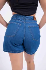 Short de jean de tiro alto, color azul medio, con bolsillos delanteros y traseros, y ruedo desflecado.
