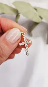 Dije de plata con forma de cruz, adornado con circonias.