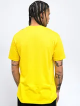 Remera amarilla con una franja vertical negra en el lado izquierdo. En la parte superior de la franja se encuentra el escudo del Club Atlético Peñarol. En la parte inferior de la franja se lee la leyenda "Oro y Carbón".