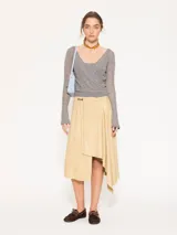 Sweater gris compuesto por un top inferior de breteles y un sweater superior de manga larga con escote en V cruzado. Ambas piezas están confeccionadas en tejido liviano de lana mezclada.