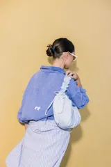 Bolso tipo cartera de nylon con diseño plisado y estampado abstracto en tonos claros.