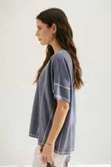 Remera azul de corte holgado con mangas cortas y costuras a la vista en color blanco.