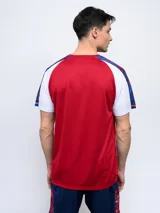 Remera de entrenamiento azul marino con detalles en blanco y rojo en los hombros y mangas. Incluye el logo de Umbro y el escudo del Club Nacional de Football en el pecho.