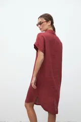 Vestido camisero midi color bordó, de lino, con cuello clásico, mangas cortas, abotonadura frontal y tajo lateral.