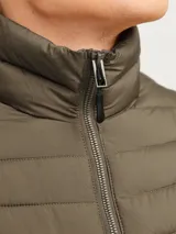 Campera puffer color verde oliva, con cuello alto y cierre frontal con cremallera. Tiene bolsillos laterales y puños elásticos.