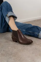 Bota corta de cuero color marrón con elásticos laterales, taco bajo y punta redondeada.