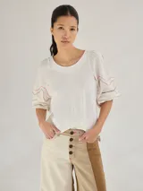 Remera gris de algodón con mangas color beige con bordados de líneas en blanco, amarillo y gris.