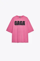 Camiseta rosa de algodón con efecto lavado, cuello redondo y manga corta. Estampado frontal con el texto "GAGA" en color negro.